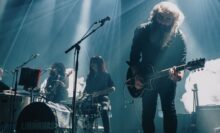 The Limiñanas performing live, Lionel Limiñana on guitar and Marie Limiñana on drums during a concert performance.