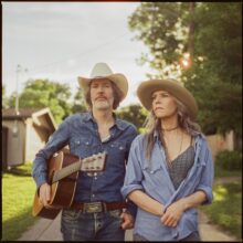 Gillian Welch and David Rawlings performing together on stage during their 2027 Australia and New Zealand tour announcement.